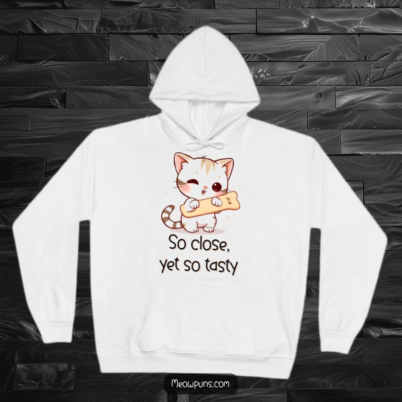 Funny hoodie print of a cute cat character poised to strike a floating fishbone, showcasing athletic pursuit and a hint of culinary ambition.